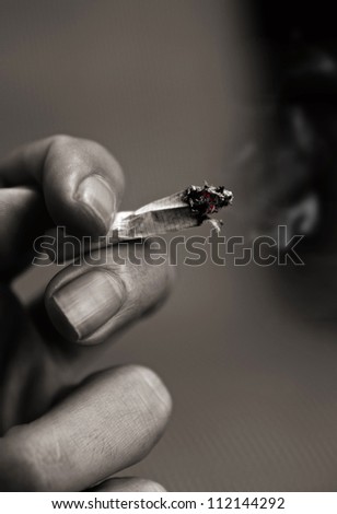 high contrast toned picture of hand with cigarette.shallow DOF