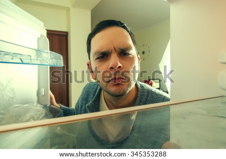 hungry man with funny face opens the fridge