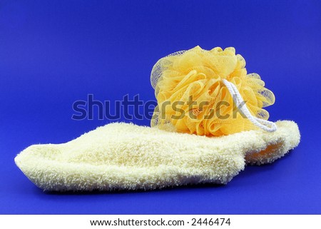 yellow body sponge and wash cloth on blue background.