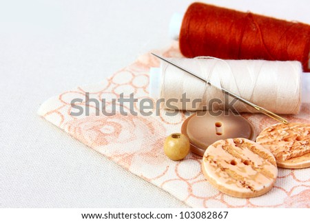 beige  spool of thread and buttons on a floral fabric