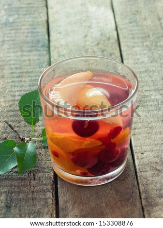 Glass of fresh fruit compote over natural wood background