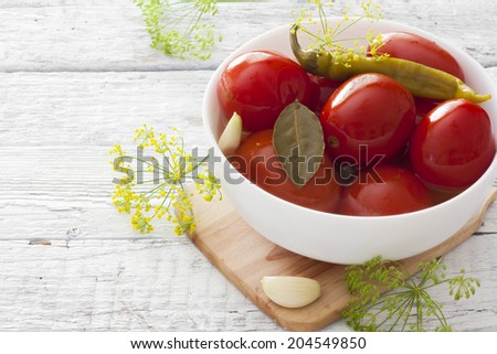 Preserved tomatoes in white bowl over white wood background