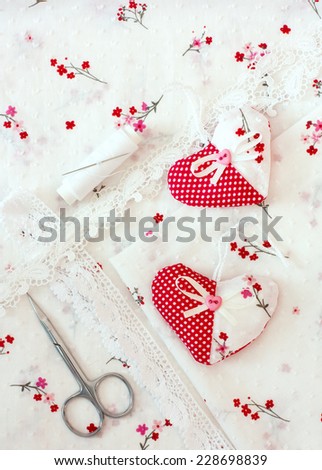 Scrapbook craft materials - laces, hearts, over cloth background with floral pattern