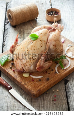 Raw whole chicken with vegetables on the wood table