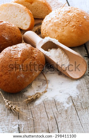 Rustic bread, wheat and flour over natural wood background