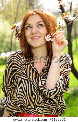 A beautiful red hair woman daydreaming in a spring beautiful spring day. Wears a animal print top.
