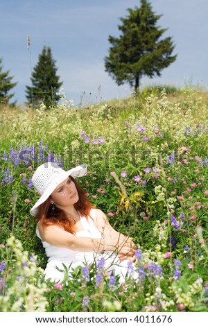 Beautiful woman resting at green meadow. Trees. Sky. Summer