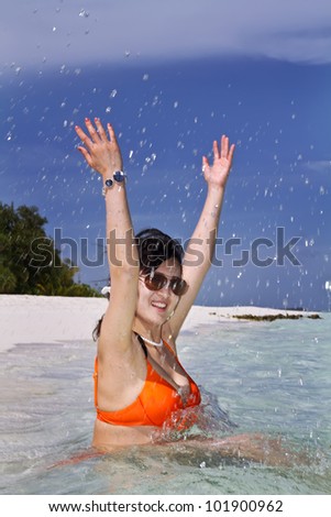 A beautiful fashion asian girl playing water in Maldive beach near the ocean in the hot summer