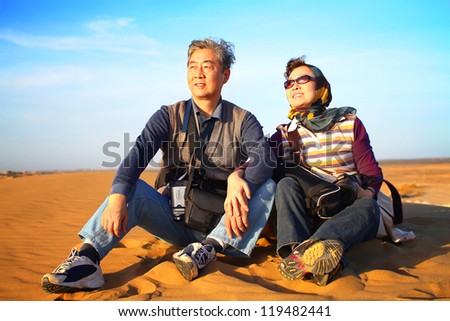 Landscape photo of senior couple sitting in desert enjoying the sunset