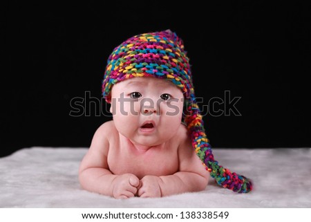 Happy cute 3-month old Chinese baby boy playing on bed with colorful suites