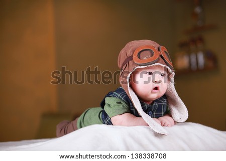 Happy cute 3-month old Chinese baby boy playing on bed with colorful suites