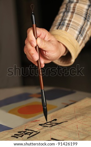An old man is practicing calligraphy using a brush pen in his leisure time. The Chinese words in the photo are : \