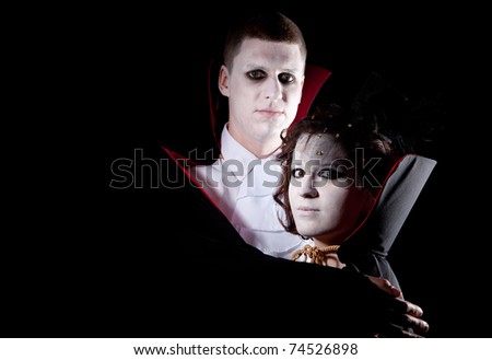 a young vampire couple posing together black background