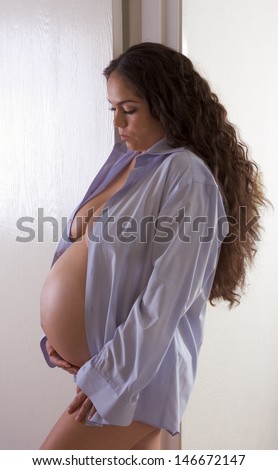 pregnancy 3 weeks before childbirth. Seminude ethnic Hispanic Latina woman with long hair standing by door