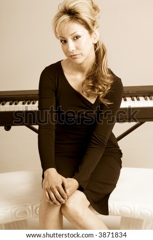 Latina female in elegant dress sitting by piano keyboard