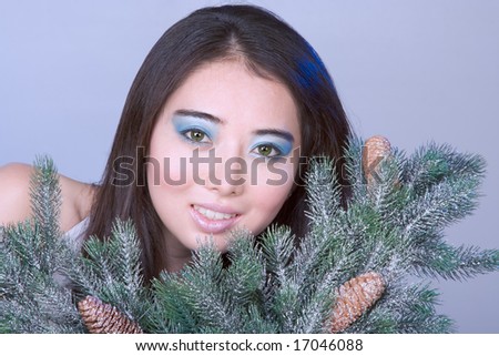 Asian girl in white dress holding branch of Christmas tree