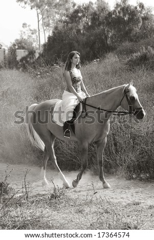 Attractive girl riding on horse in deserted rural location