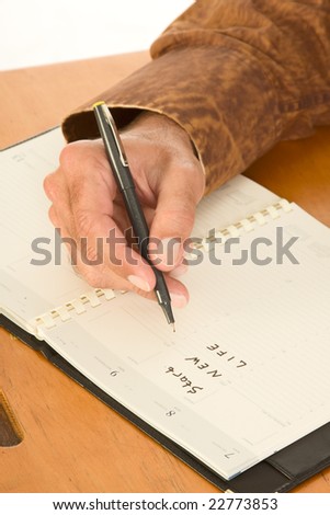 Hand on unidentifiable Caucasian man write in diary using pen planning start new life