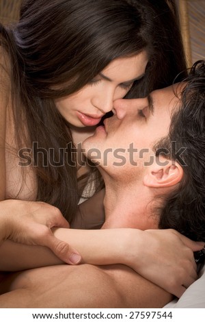 Loving affectionate nude heterosexual couple in affectionate sensual kiss. Mid adult Caucasian men in late 30s and young Hispanic woman in early 20s
