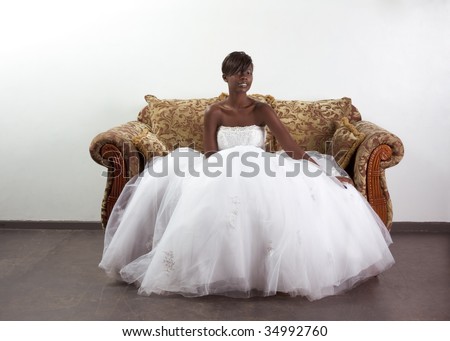  American happy female in white gorgeous wedding gown sitting on couch