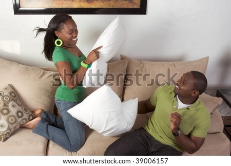 African-American man and woman fooling around engaged in pillow fight
