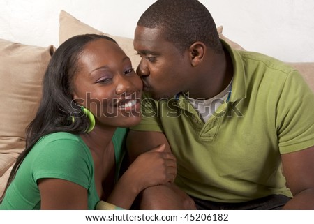 Young African American couple sitting in living room on couch enjoying time together