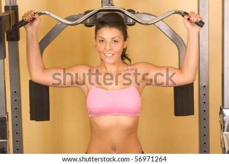 Attractive young female working out on weight-lifting training machine