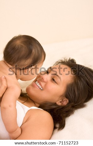 Mom and son on bed and mother embracing the infant baby playing with him