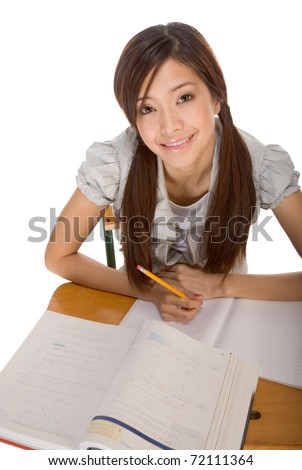 Asian student girl sitting by the desk and studying huge math book, preparing to test