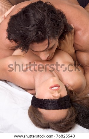 Loving affectionate heterosexual couple in affectionate sensual kiss. Woman eyes are covered by black scarf