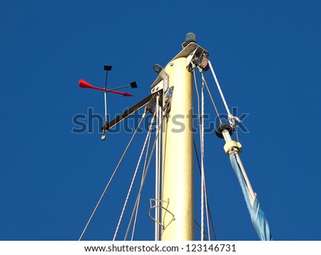 The top of a sailing ships mast against a blue sky