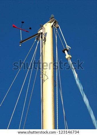 The top of a sailing ships mast against a blue sky