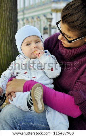 Baby sits on mother lap and eats corn ball