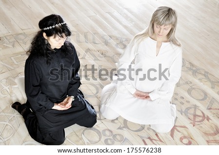 Two young woman black and white dressed doing yoga