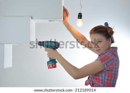 Beautiful young woman uses an electric drill