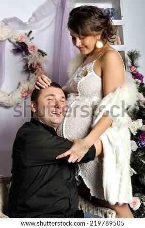 Young pregnant woman and happy father decorating Christmas tree