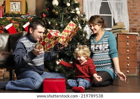 Smiling parents giving Christmas present to son at home