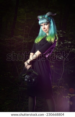 Beautiful woman with color hair and horns in the forest holds a black bouquet