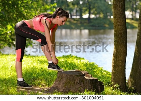 Sports girl ties laces in park, after workout training
