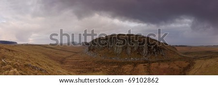 Panoramic shot of Hadrian\'s Wall at Steel Rigg in Northumberland taken under a heavy grey sky.