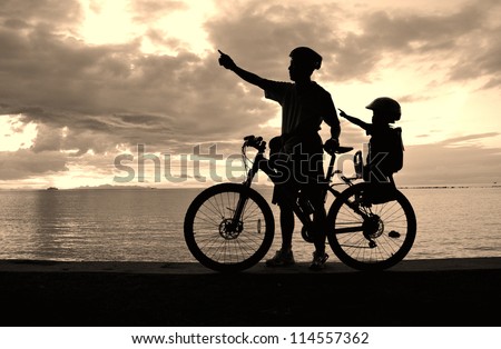 Family silhouette , daughter on child seat with parent at the beach at sunset.