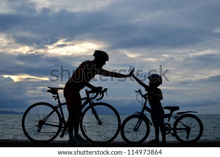 Biker family silhouette , daddy and son at the beach at sunset.