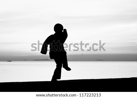 Silhouette taekwondo boy on the beach at dusk. Black and whit picture.