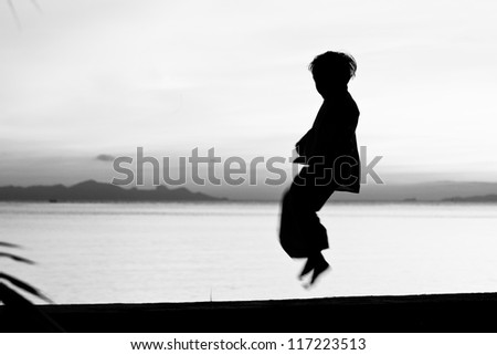 Silhouette taekwondo boy on the beach at dusk. Black and whit picture.