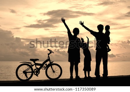 Biker family silhouette  at the beach at sunset.