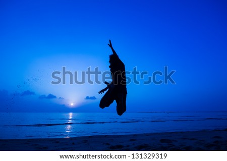 silhouette of happy man jumping at the beach.