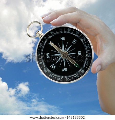 Classic compass in lady hand on sky background.