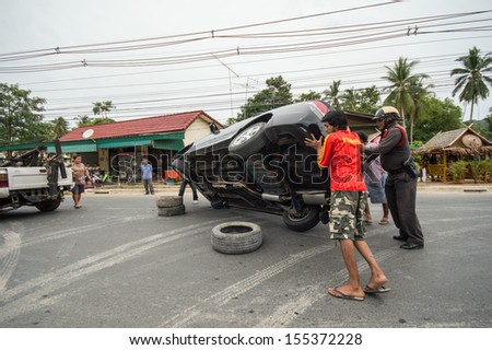 KO SAMUI, THAILAND - SEPTEMBER 22: Black color sedan car with an accident with rescue team on September 22, 2013 in Ko samui, Thailand.