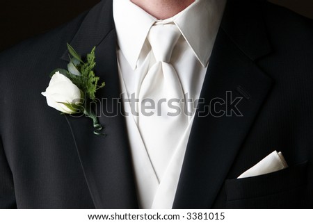  boutonniere pinned on the collar of a black wedding suit with white