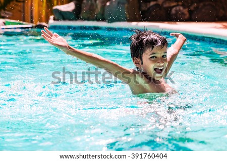 Young boy kid child eight years old splashing in swimming pool having fun leisure activity open arms